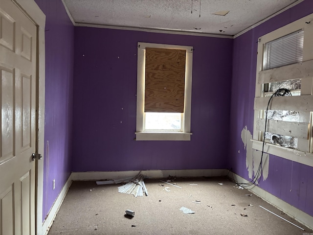 spare room with crown molding, a textured ceiling, and baseboards