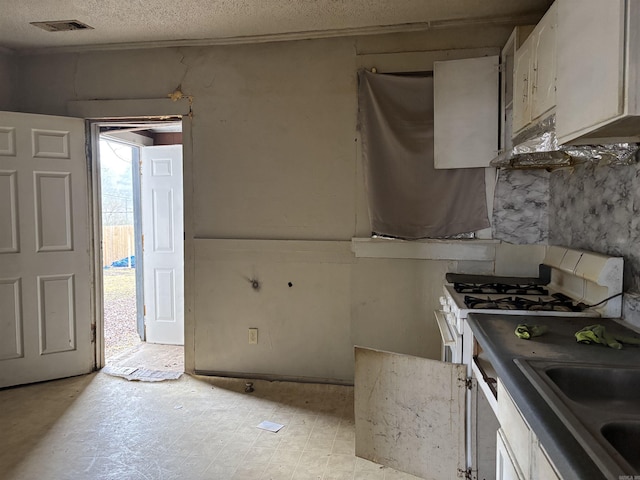 kitchen with visible vents, white cabinets, a sink, a textured ceiling, and white range with gas stovetop