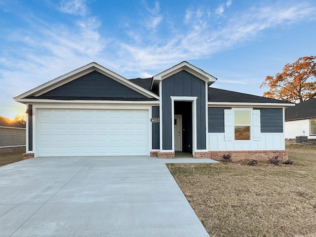 ranch-style home featuring a garage, cooling unit, and a front lawn