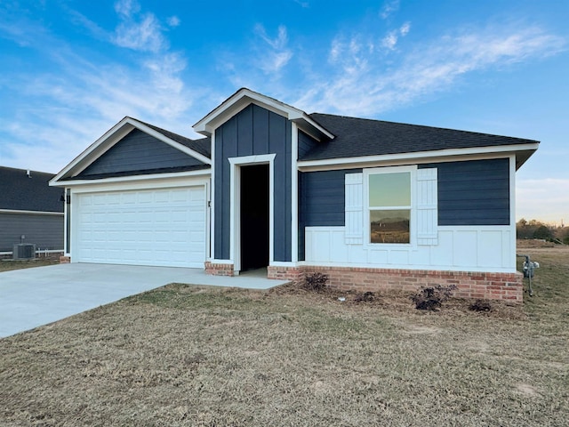 view of front of home featuring a garage, central air condition unit, and a front lawn