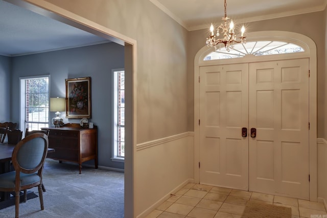 entrance foyer featuring ornamental molding, a healthy amount of sunlight, an inviting chandelier, and light tile patterned floors