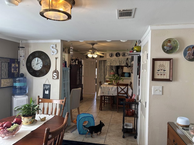 tiled dining area with ceiling fan and ornamental molding