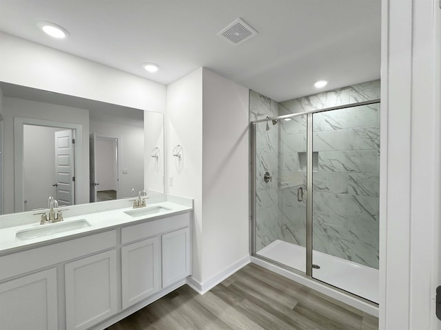 bathroom featuring hardwood / wood-style floors, a shower with door, and vanity