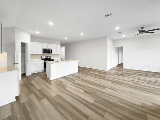 kitchen featuring white cabinetry, stainless steel appliances, an island with sink, sink, and light hardwood / wood-style flooring