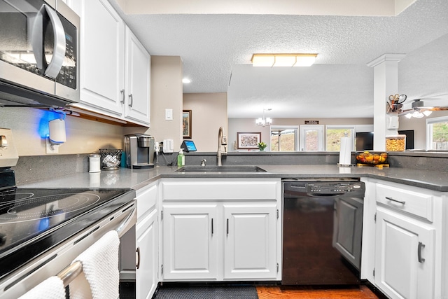 kitchen with appliances with stainless steel finishes, sink, white cabinets, ceiling fan with notable chandelier, and a textured ceiling