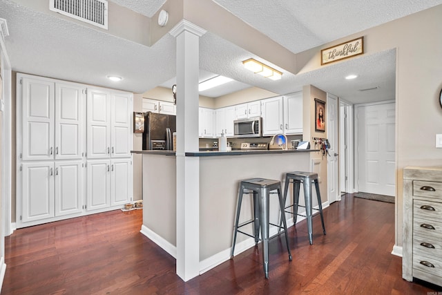 kitchen featuring kitchen peninsula, white cabinets, a textured ceiling, and black refrigerator with ice dispenser