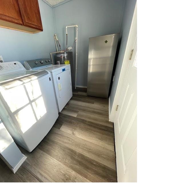 laundry room with electric water heater, dark hardwood / wood-style flooring, cabinets, and washer and dryer