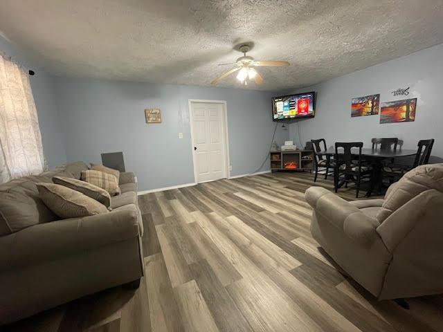 living room featuring hardwood / wood-style flooring, a textured ceiling, and ceiling fan