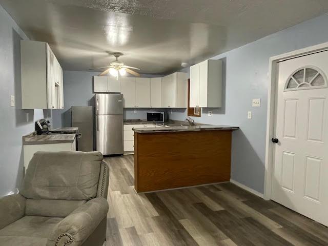 kitchen with dark hardwood / wood-style flooring, white cabinetry, ceiling fan, and stainless steel appliances