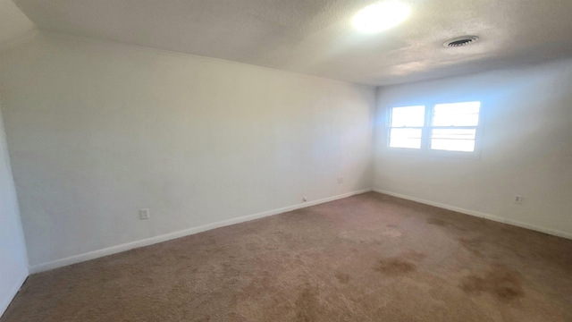 carpeted empty room with a textured ceiling