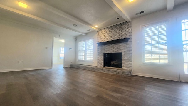 unfurnished living room featuring a wealth of natural light, dark hardwood / wood-style floors, beam ceiling, and a fireplace