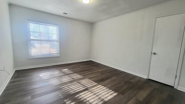 empty room with a textured ceiling and dark hardwood / wood-style flooring