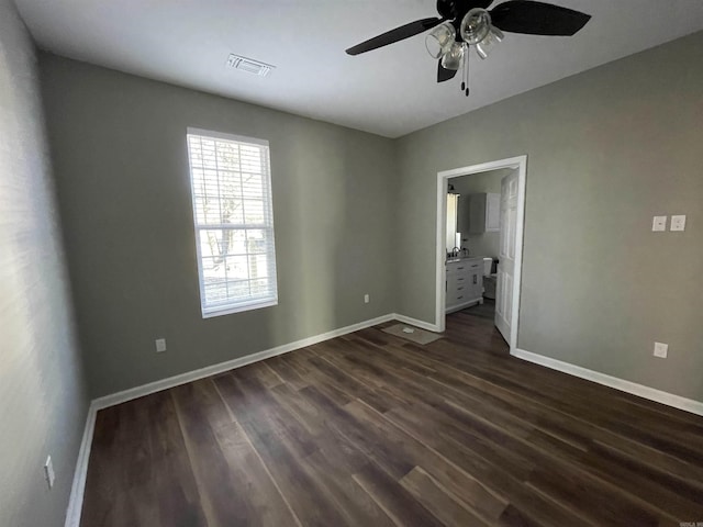 unfurnished bedroom with ceiling fan, ensuite bathroom, and dark hardwood / wood-style flooring