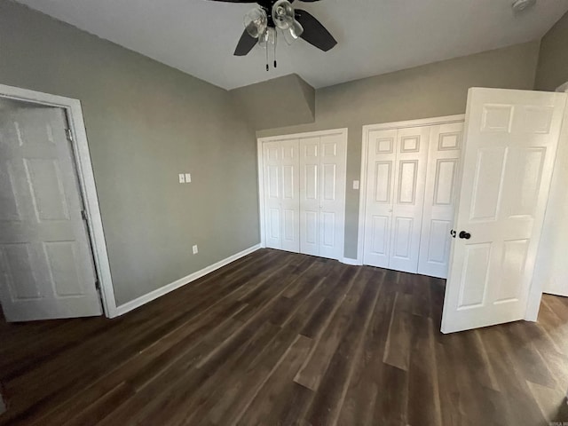 unfurnished bedroom featuring multiple closets, ceiling fan, and dark hardwood / wood-style flooring