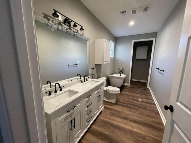 bathroom with wood-type flooring, toilet, a bath, and vanity