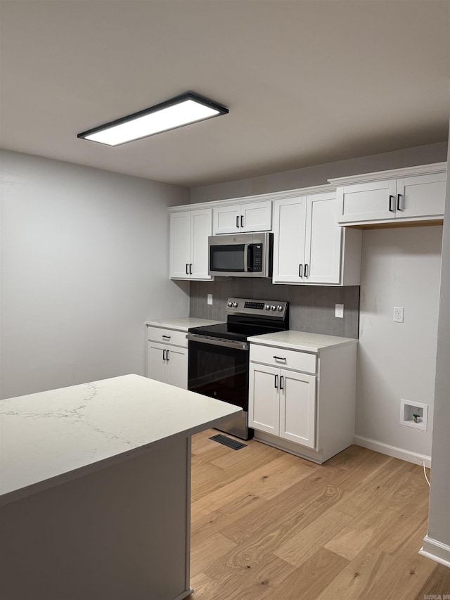 kitchen featuring appliances with stainless steel finishes, white cabinets, and light wood-type flooring