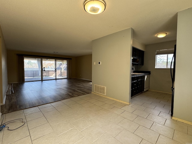 unfurnished room featuring sink, a healthy amount of sunlight, and light tile patterned floors