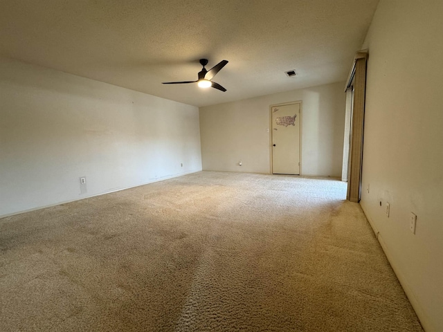 empty room with ceiling fan, a textured ceiling, and light carpet