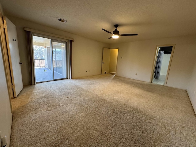 carpeted spare room featuring a textured ceiling and ceiling fan