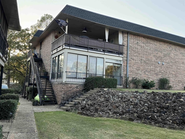 view of side of property with a balcony, a sunroom, and ceiling fan