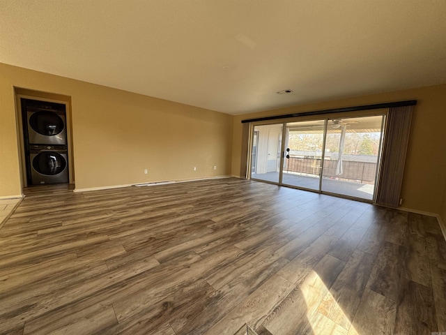 unfurnished living room with wood-type flooring and stacked washing maching and dryer