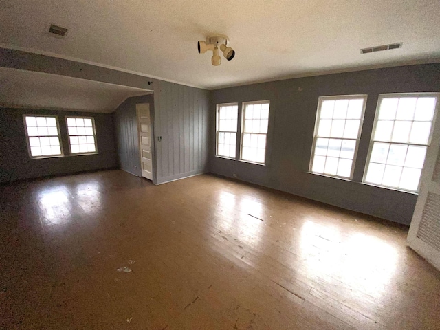 unfurnished living room with a textured ceiling, a healthy amount of sunlight, hardwood / wood-style flooring, and lofted ceiling