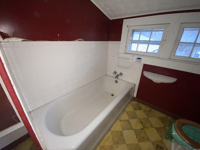 bathroom with a tub, toilet, and crown molding