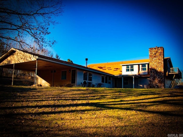 rear view of property featuring a sunroom, a lawn, and a carport