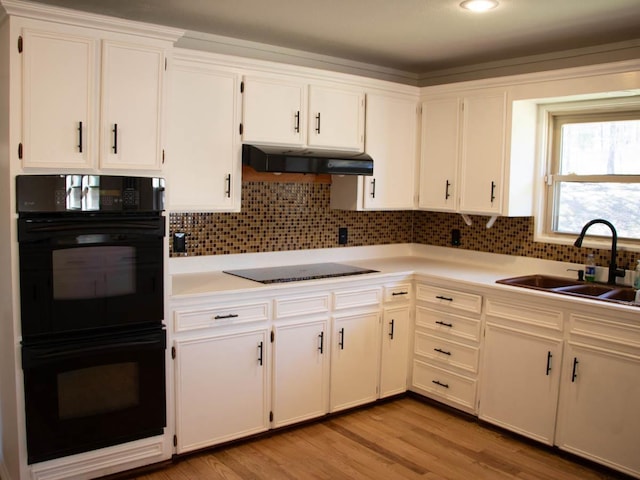 kitchen with black appliances, extractor fan, white cabinetry, light wood-type flooring, and sink