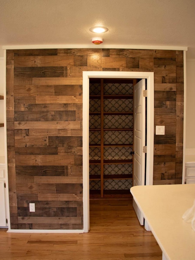 details featuring wood walls, a textured ceiling, and wood-type flooring