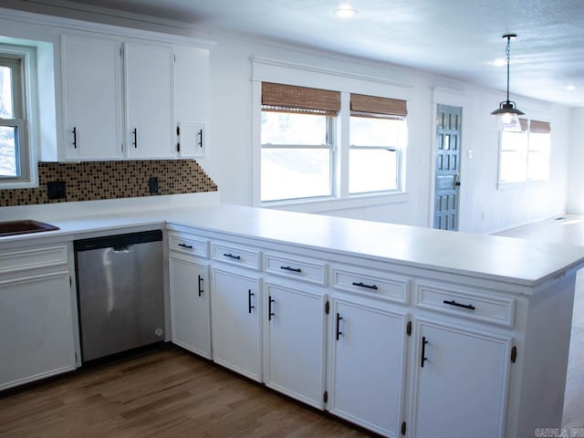 kitchen featuring tasteful backsplash, stainless steel dishwasher, white cabinets, kitchen peninsula, and pendant lighting