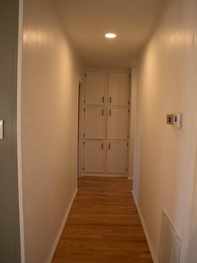 hallway with light hardwood / wood-style flooring and ornamental molding