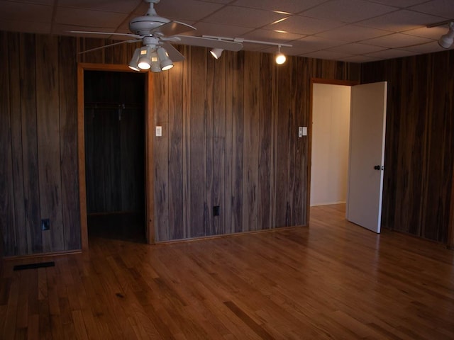 spare room featuring ceiling fan, hardwood / wood-style floors, and wooden walls