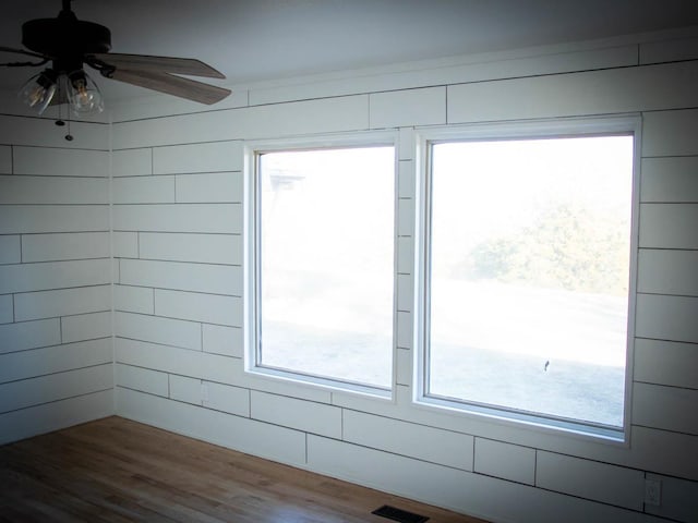 interior space featuring ceiling fan, wooden walls, and wood-type flooring