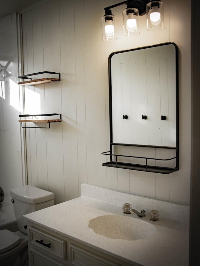 bathroom featuring vanity, toilet, and wood walls