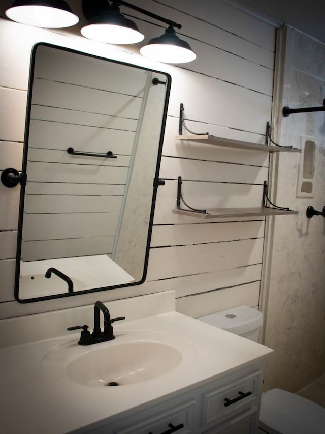 bathroom with vanity, toilet, and wooden walls