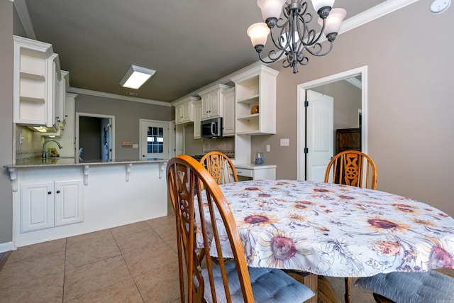 dining space with sink, light tile patterned floors, crown molding, and a chandelier