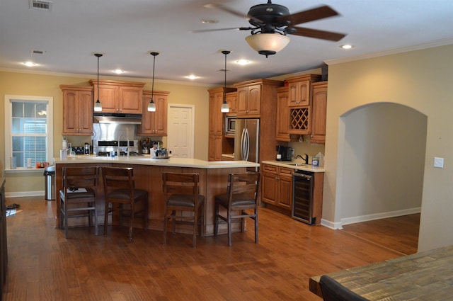 kitchen featuring hanging light fixtures, crown molding, beverage cooler, and appliances with stainless steel finishes