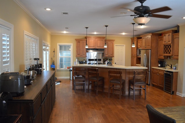 kitchen featuring hanging light fixtures, dark wood-type flooring, stainless steel fridge, and beverage cooler