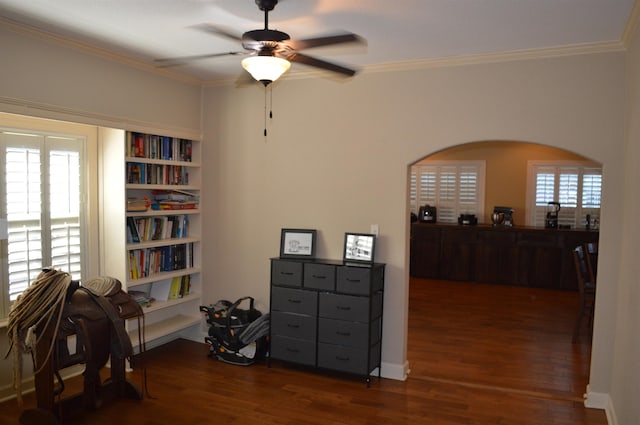 interior space with ceiling fan, ornamental molding, and dark wood-type flooring