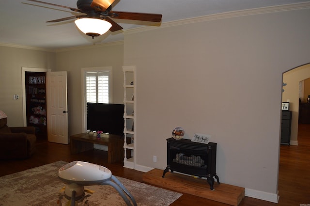 living room with dark wood-type flooring, a wood stove, ornamental molding, and ceiling fan