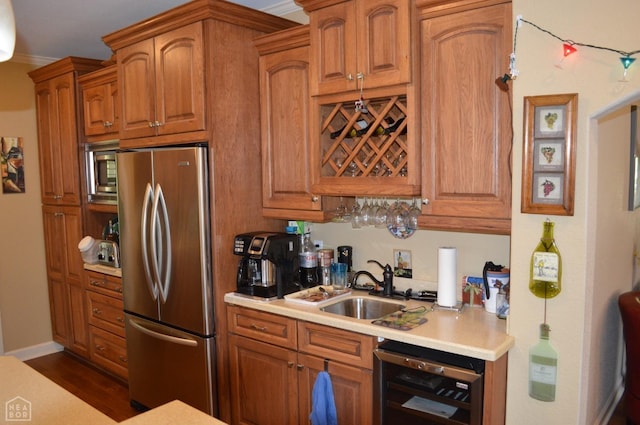 kitchen with beverage cooler, appliances with stainless steel finishes, sink, hardwood / wood-style flooring, and crown molding