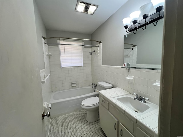 full bathroom featuring tile patterned floors, tile walls, tiled shower / bath combo, toilet, and vanity