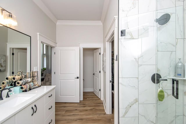 bathroom with wood-type flooring, ornamental molding, a shower with shower door, and vanity