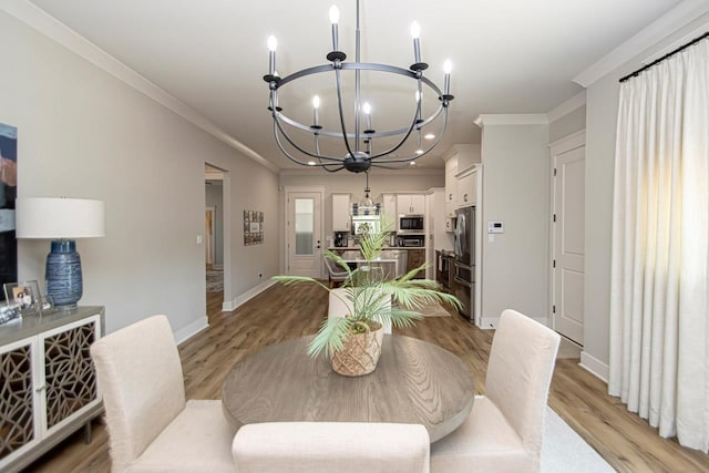 dining space featuring light hardwood / wood-style floors, crown molding, and a notable chandelier