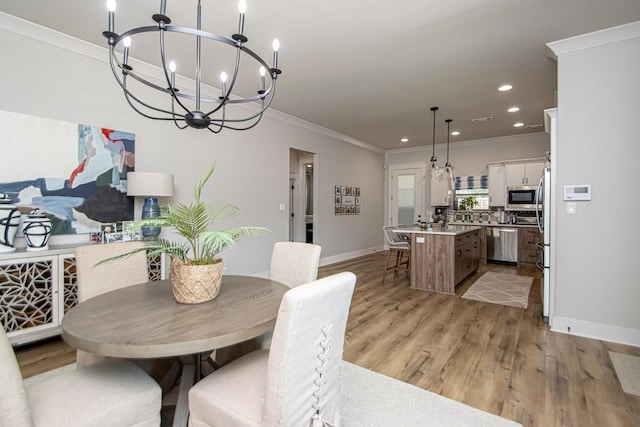 dining space featuring light wood-type flooring, a chandelier, and ornamental molding