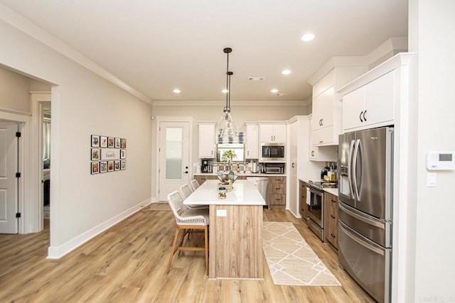 kitchen with pendant lighting, white cabinets, appliances with stainless steel finishes, a center island, and a kitchen breakfast bar