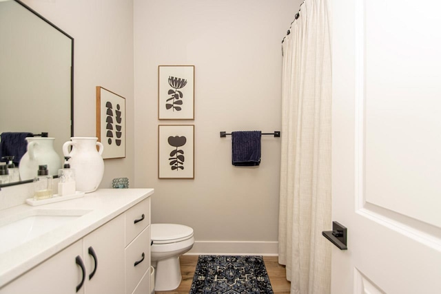 bathroom featuring wood-type flooring, toilet, and vanity