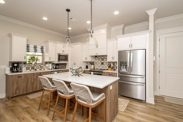 kitchen featuring white cabinetry, hanging light fixtures, sink, a kitchen island, and stainless steel appliances