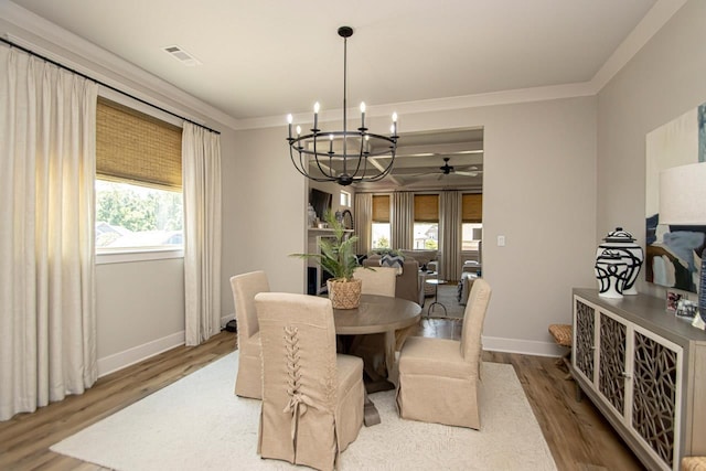 dining space featuring wood-type flooring, an inviting chandelier, and crown molding